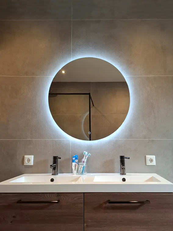 Moderne badkamer met vrijstaand ligbad, wandtoilet, grijze wandtegels, lichte vloertegels en raam.