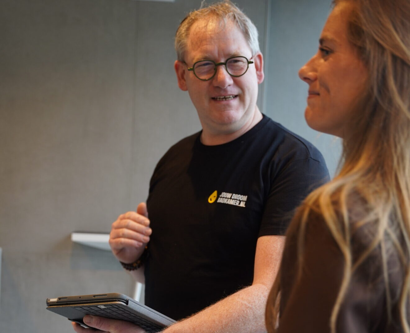 Badkameradviseur in gesprek met klant tijdens persoonlijk advies in moderne showroom.