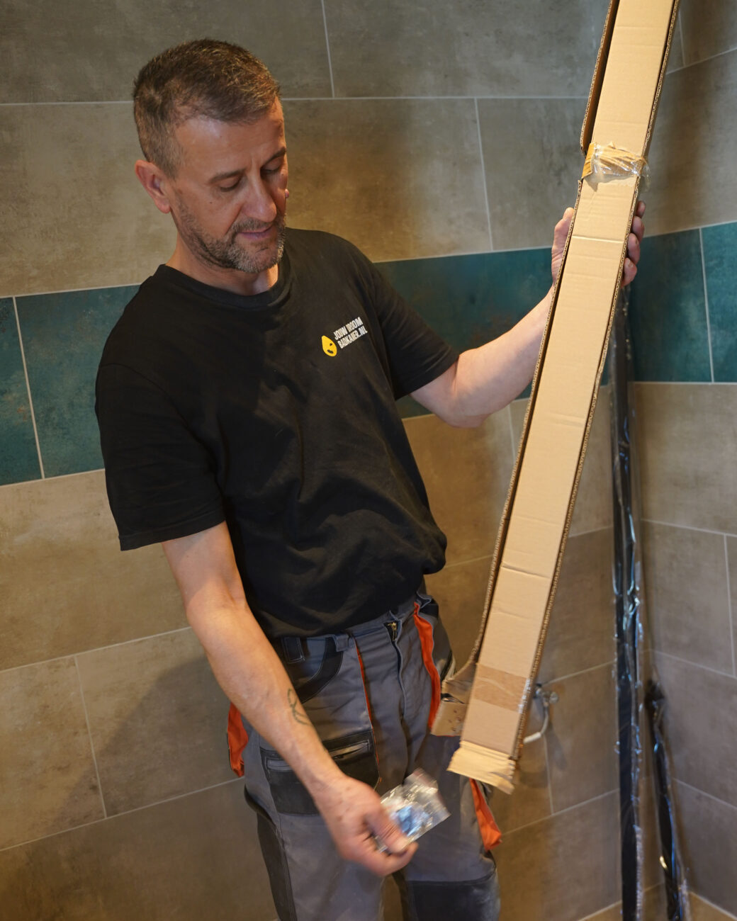 Monteur van Jouw Droombadkamer installeert badkameronderdelen in een moderne badkamer.