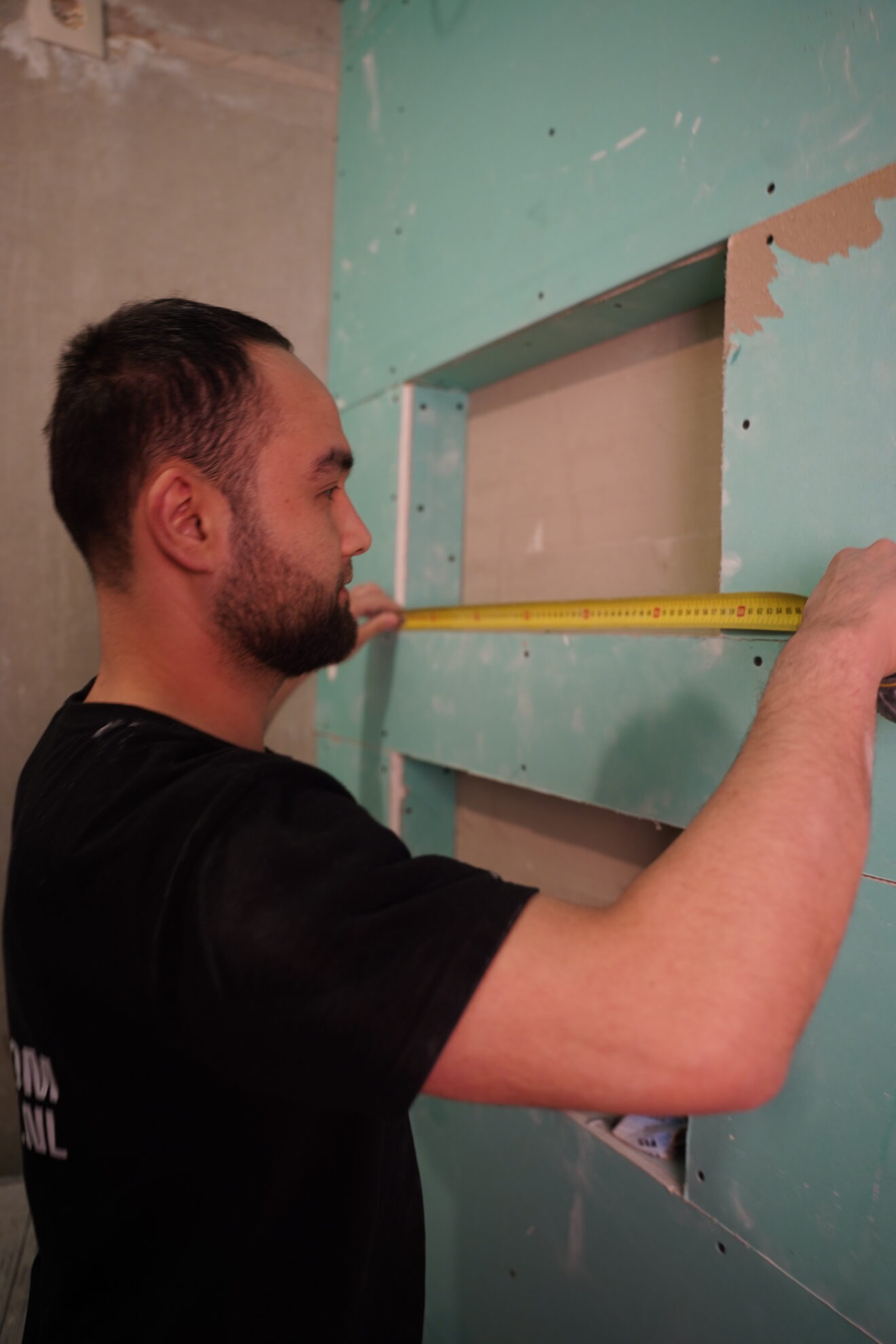 Monteur van Jouw Droombadkamer meet een nisconstructie tijdens badkamerinstallatie.