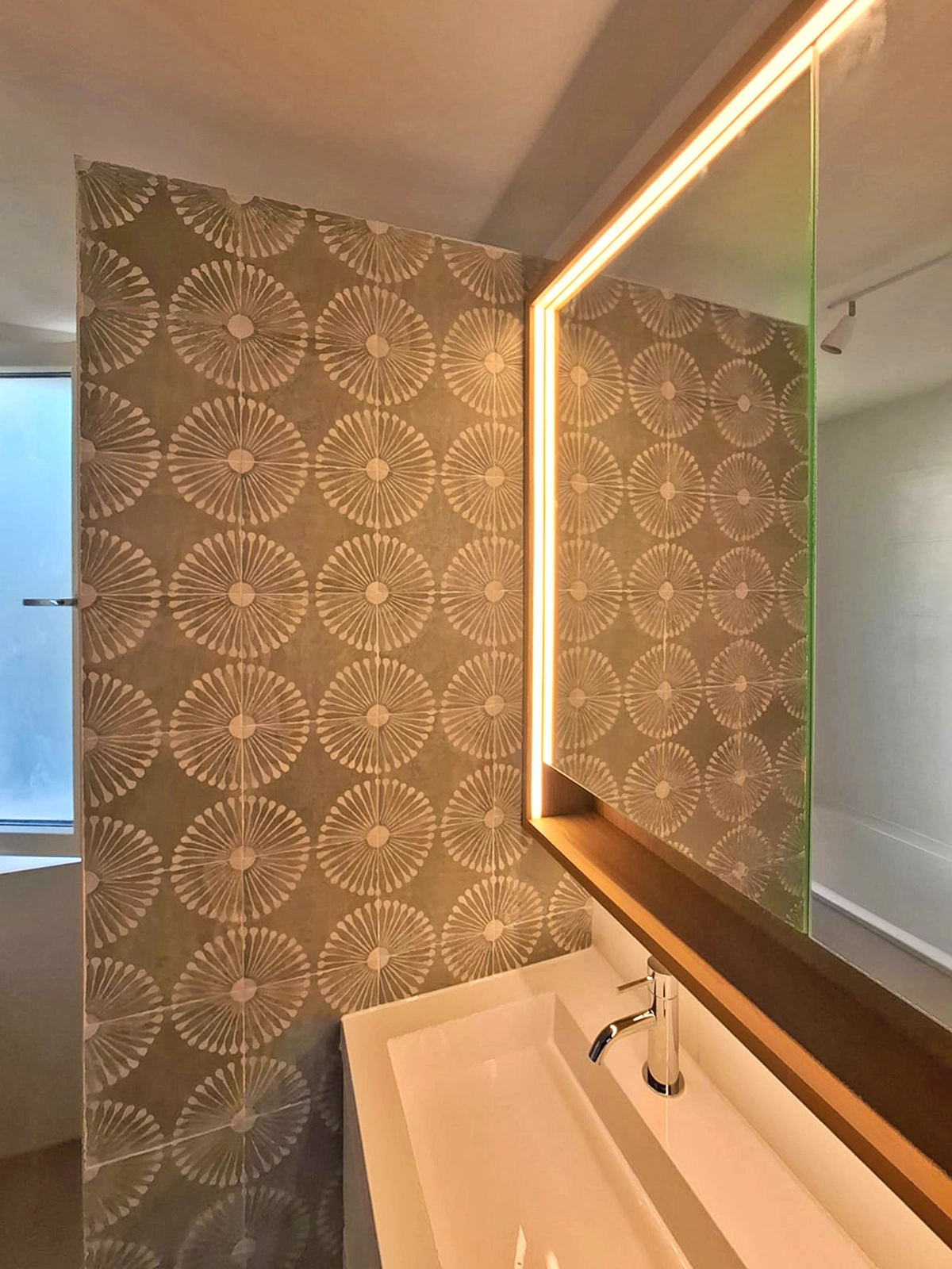 Modern badkamermeubel met verlichte spiegel en decoratieve patroonwandtegels.