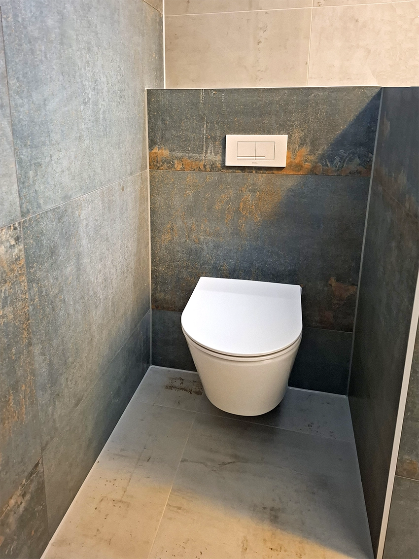 Modern toilet met industriële wandtegels, zwevend toilet en donkere betonlook afwerking.