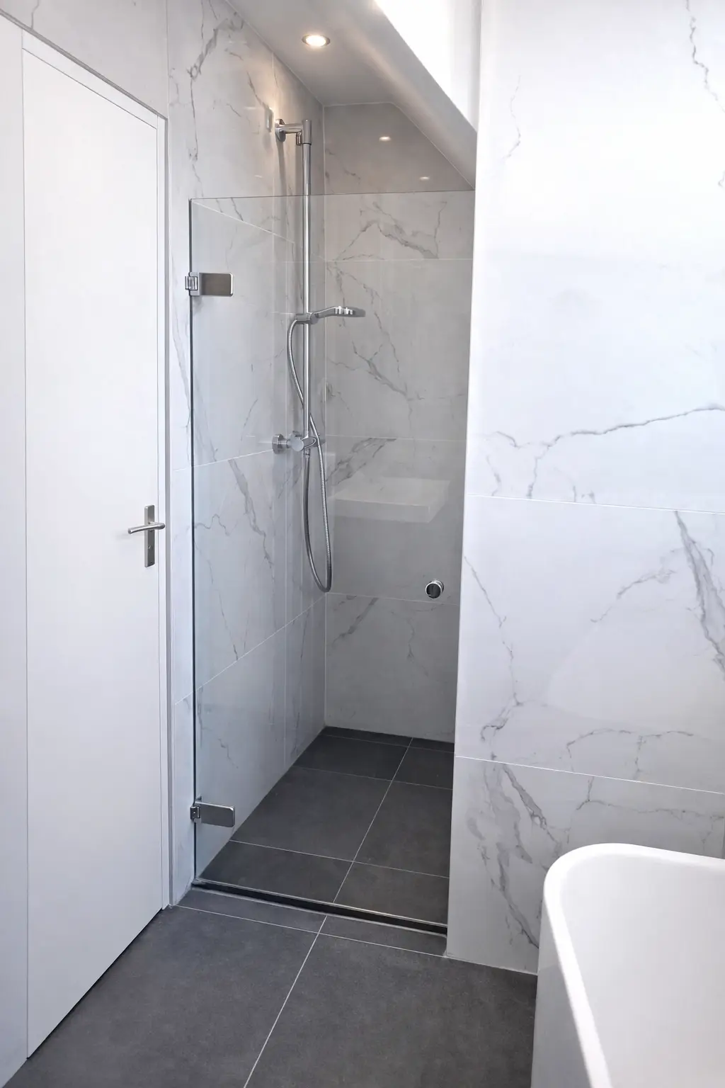 Moderne inloopdouche met marmerlook wandtegels, glazen douchewand en donkere vloertegels.