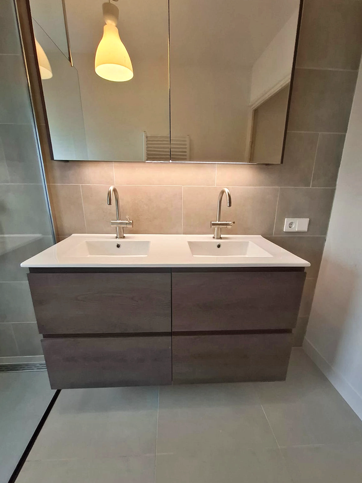 Modern dubbel badkamermeubel met twee wastafels, grote spiegelkast en beige wandtegels.