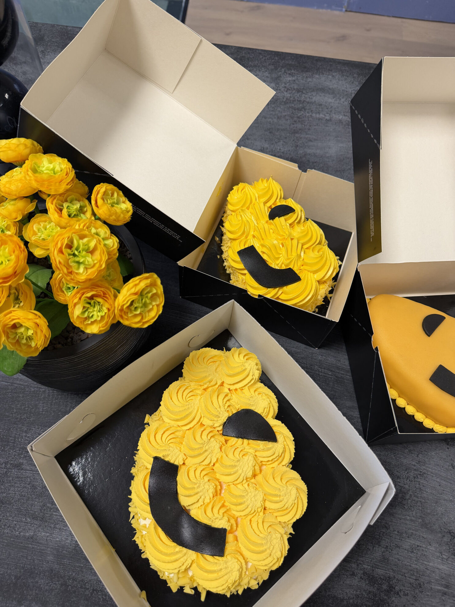 Gele taarten met Jouw Droombadkamer logo in open cadeauverpakkingen naast gele bloemen.