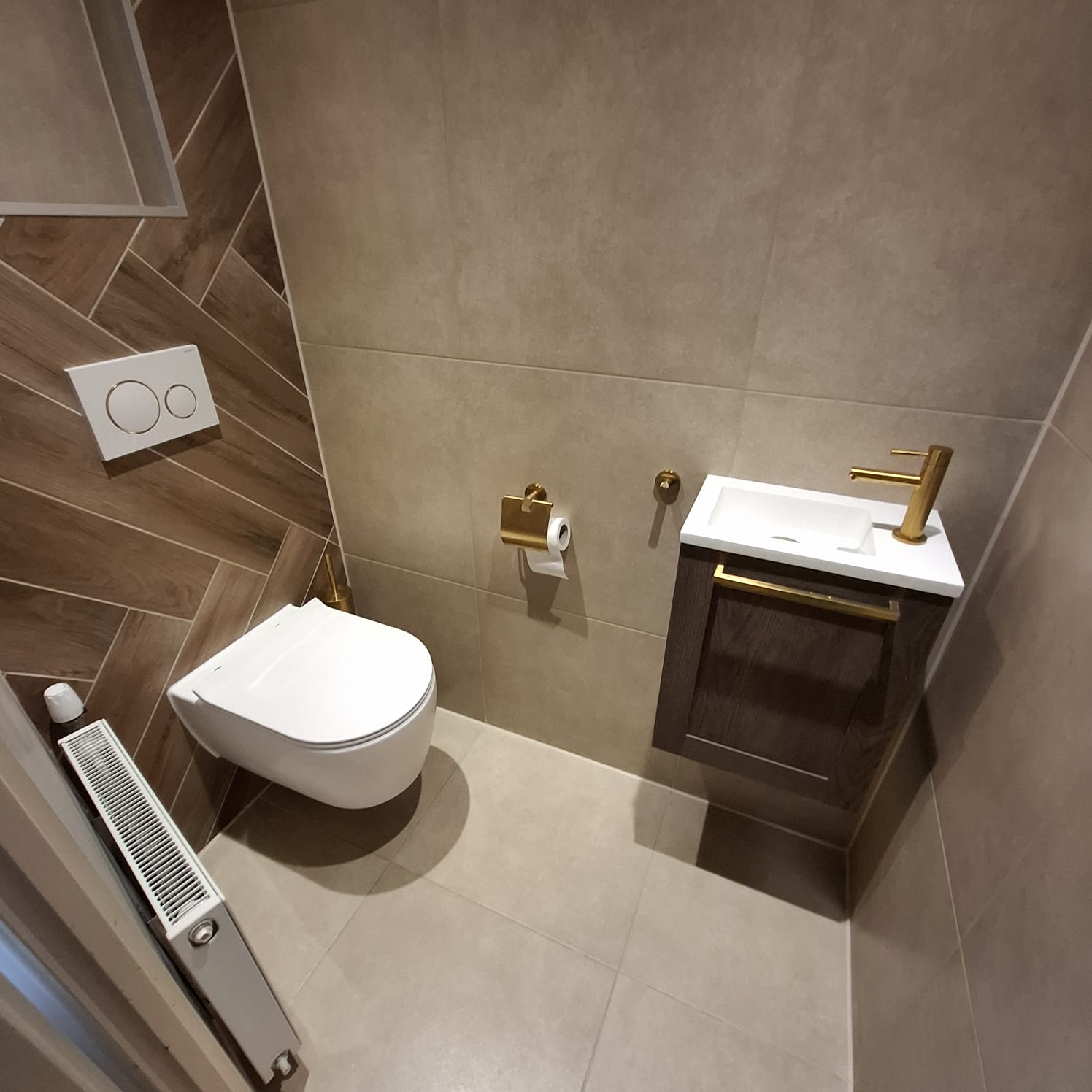 Luxe toiletruimte met zwevend toilet, compact fonteintje en goudkleurige accenten.