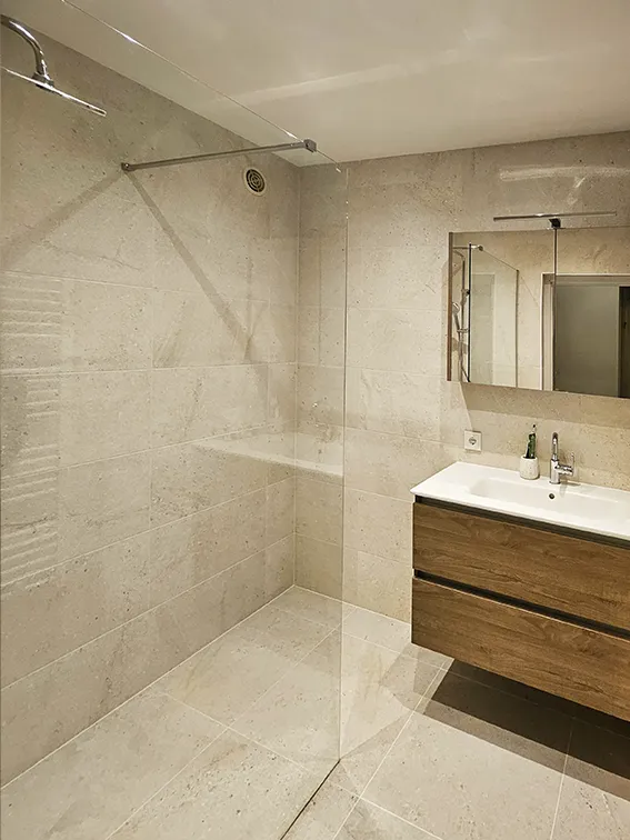 Moderne badkamer met ruime inloopdouche, beige tegels en houten badkamermeubel.