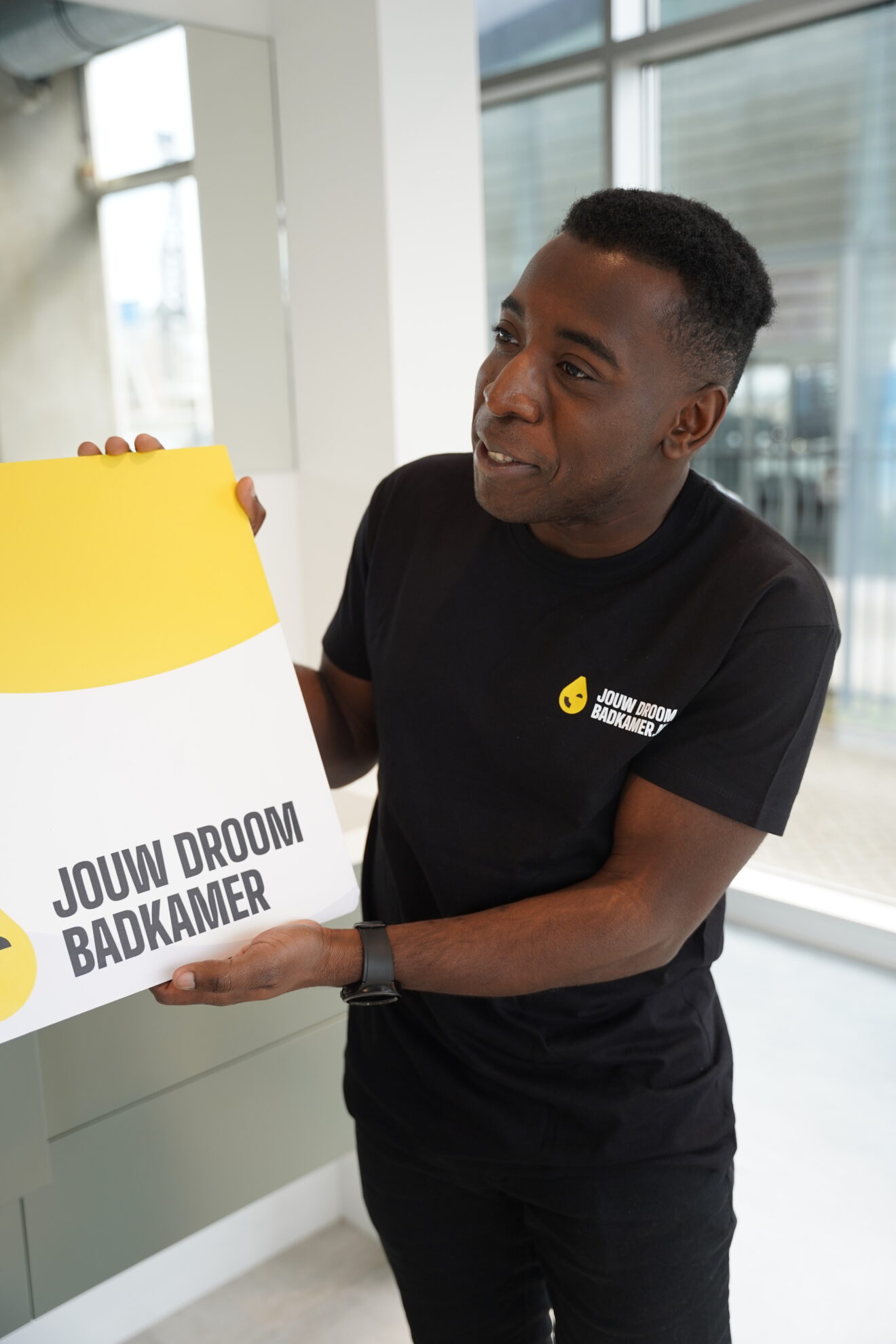 Medewerker van Jouw Droombadkamer presenteert een branded tas in een moderne showroom.