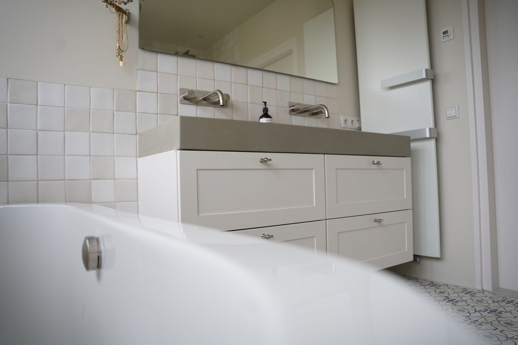 Moderne badkamer met wit badkamermeubel, dubbele wastafel en lichte wandtegels.