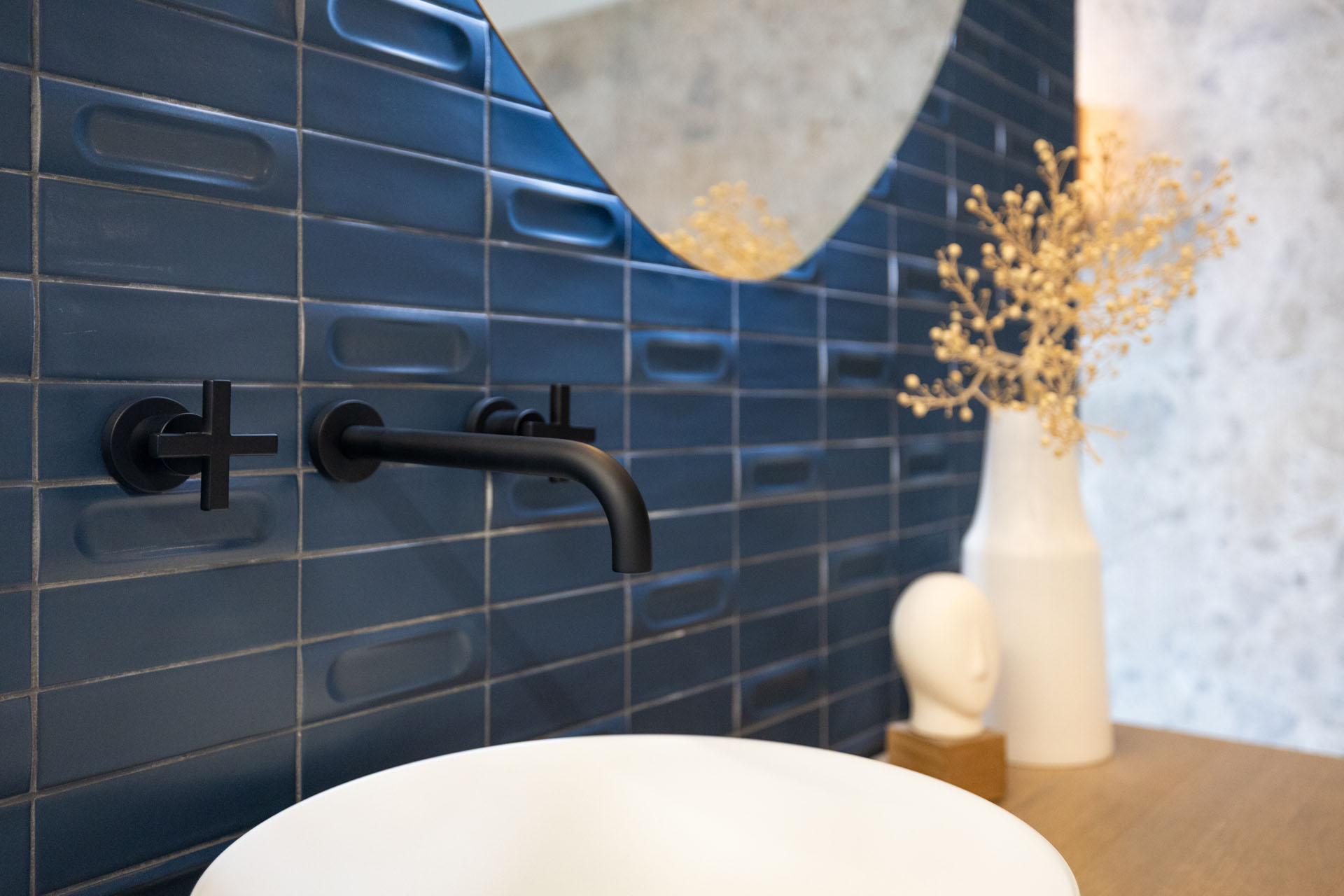 Moderne badkamer met matzwarte inbouwkraan, blauwe wandtegels en witte waskom.
