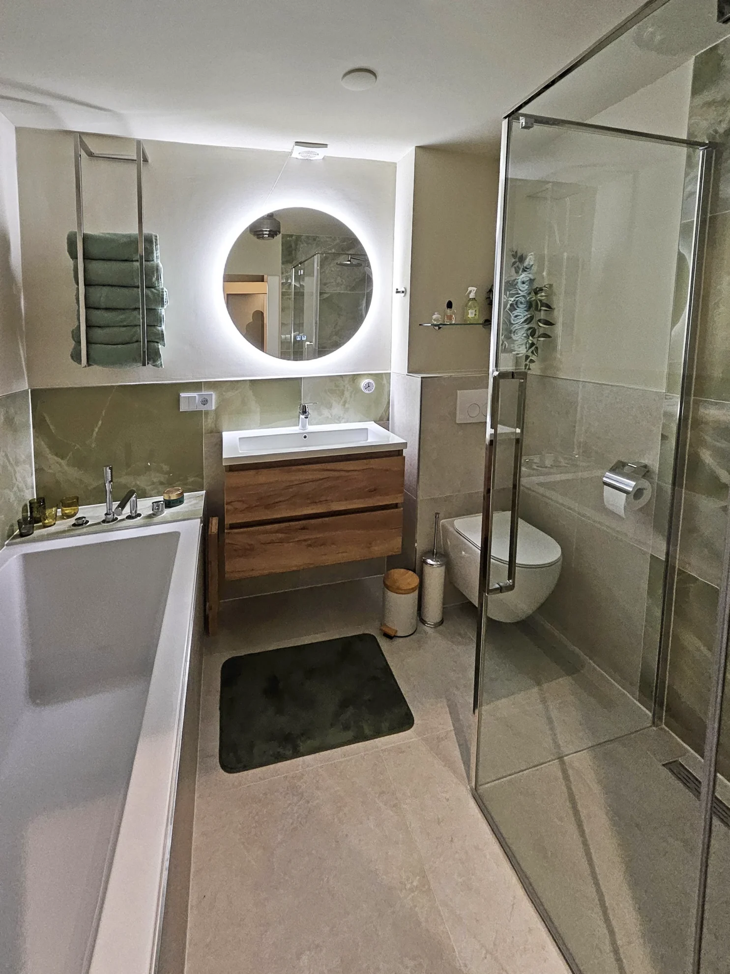 Moderne badkamer met vrijstaand bad, glazen inloopdouche en houten badkamermeubel met ronde spiegel.