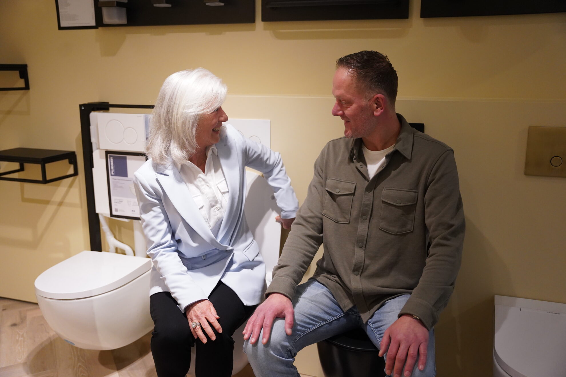Adviseur en klant bespreken sanitaire oplossingen in een moderne badkamer showroom.