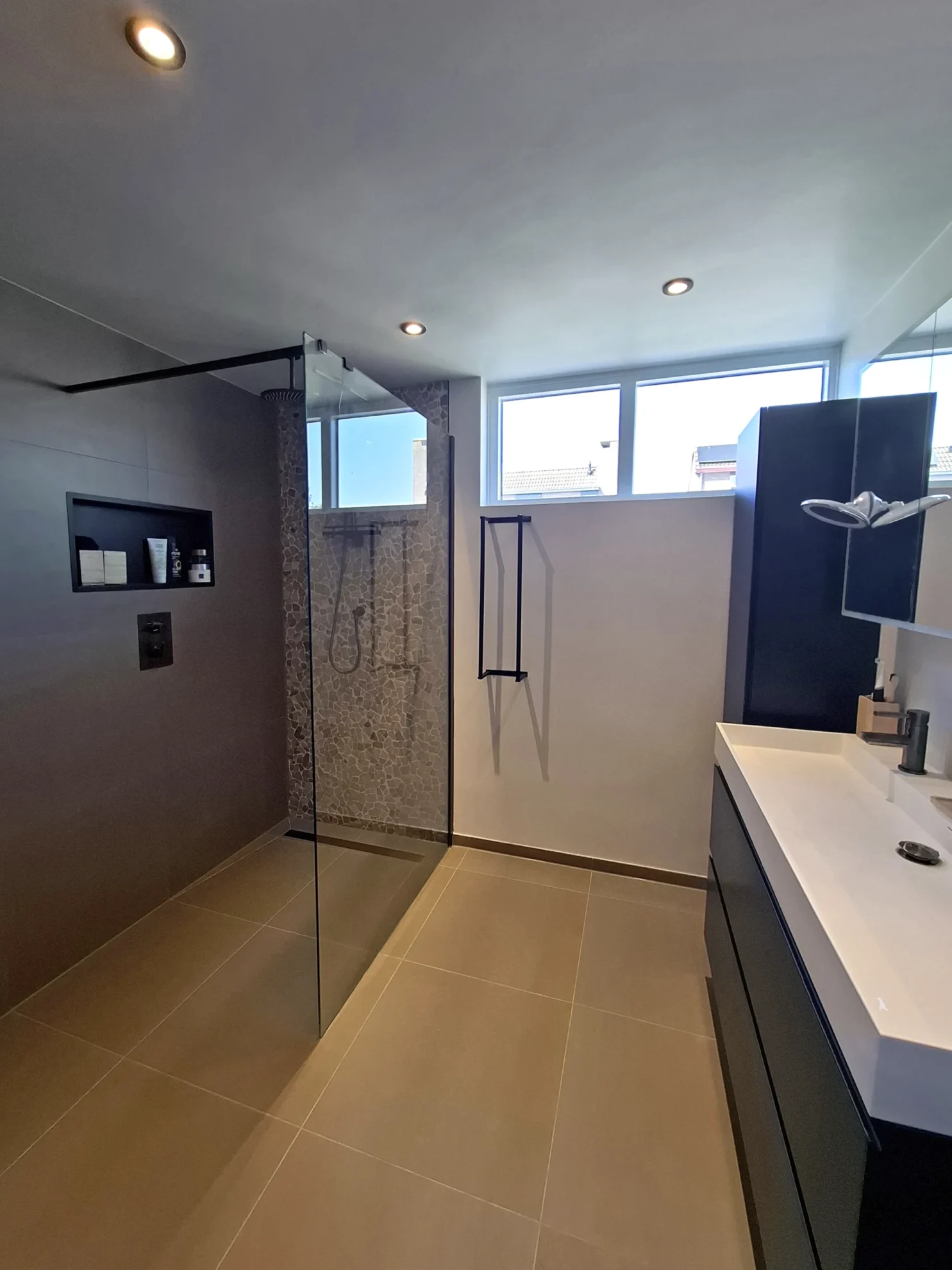 Moderne badkamer met inloopdouche, nis en wastafelmeubel met zwarte accenten.