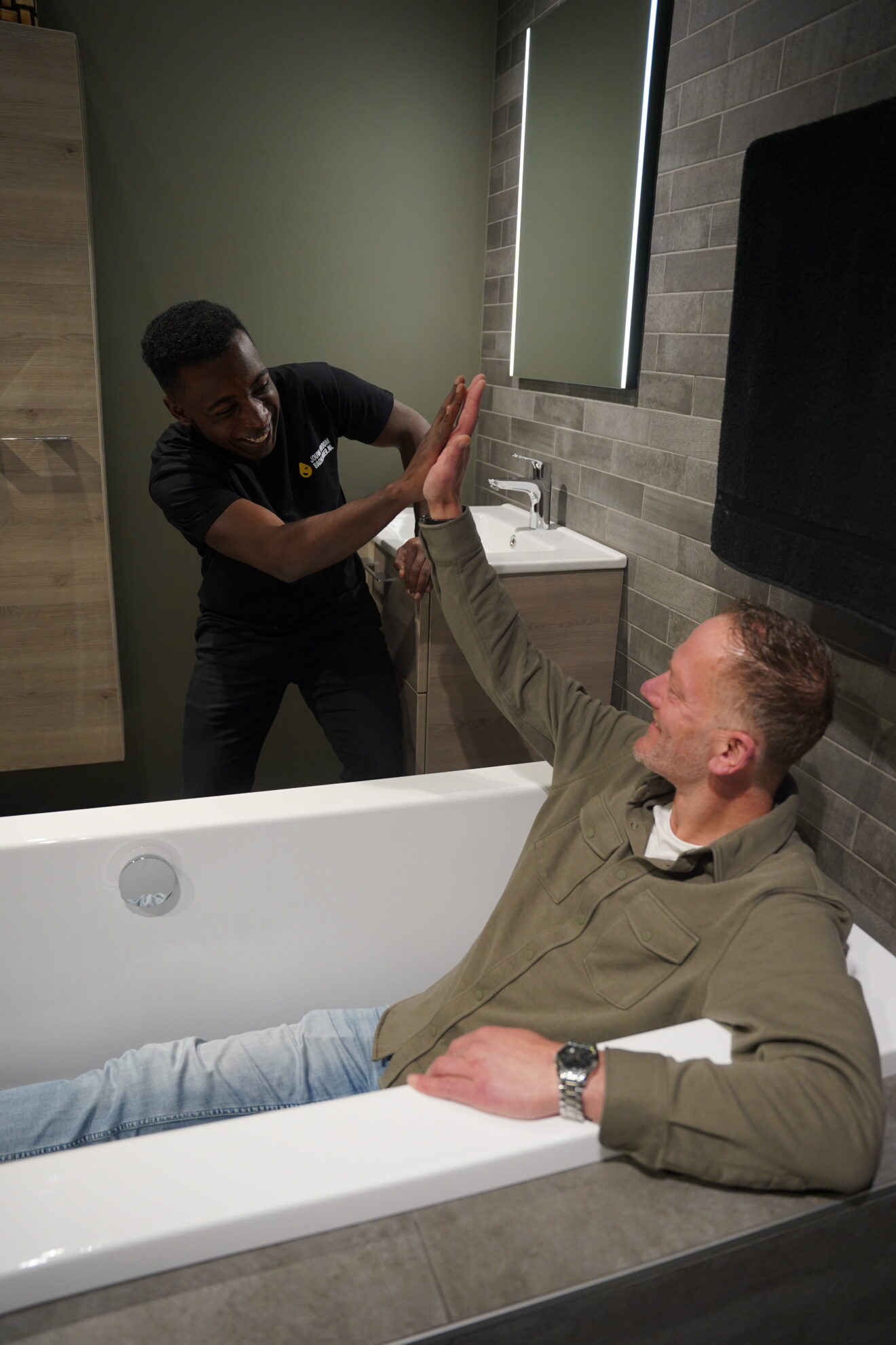 Tevreden klant en badkameradviseur geven high five in moderne badkamer