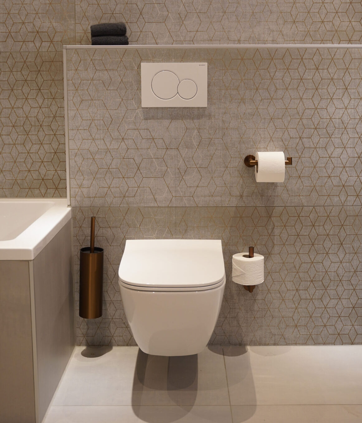 Modern hangtoilet met geometrische wandtegels en bronzen accessoires