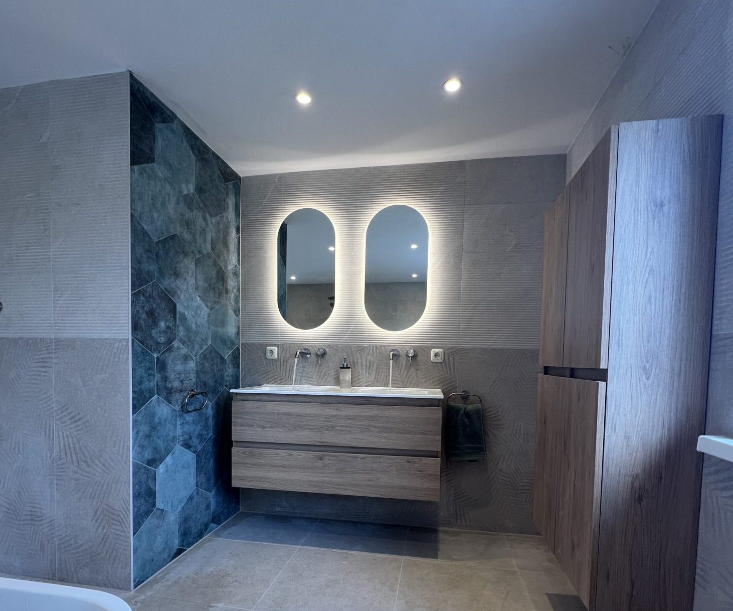 Moderne badkamer met dubbele wastafel, verlichte spiegels en houtlook badkamermeubel