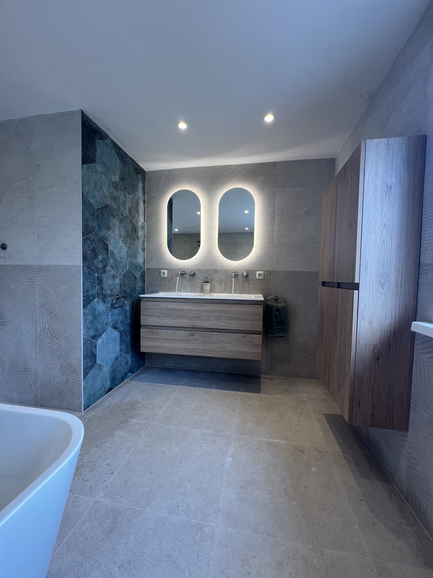 Moderne badkamer met dubbele wastafel, verlichte spiegels en houtlook badkamermeubel