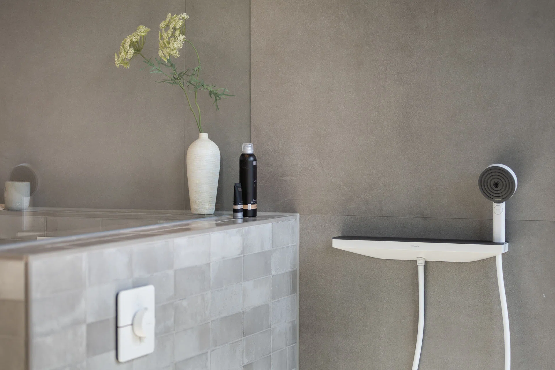 Luxe badkamer met grijze wandtegels, glanzende tegelwand, doucheaccessoires en decoratieve vaas
