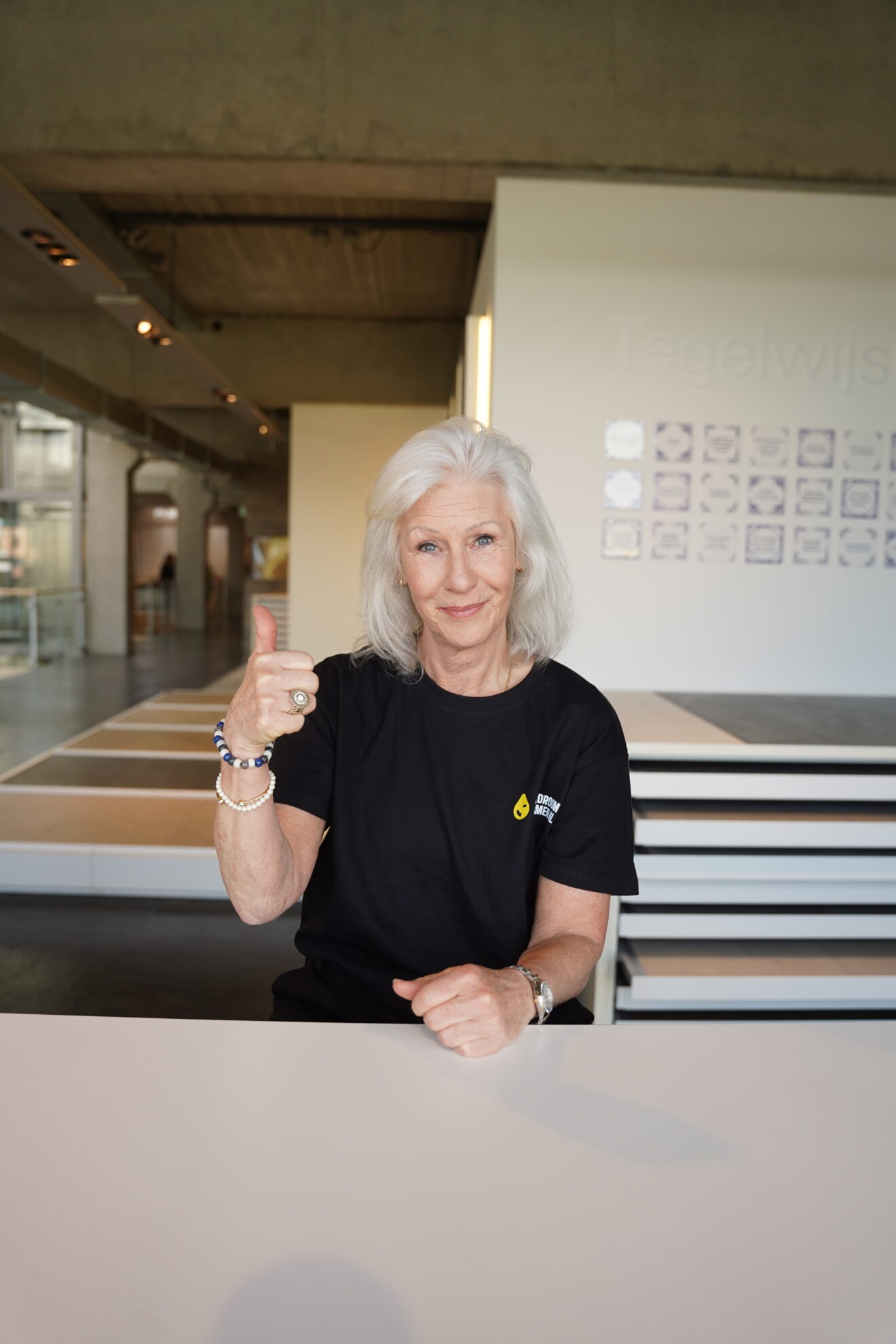 Medewerker van Jouw Droombadkamer zit aan een tafel in een showroom met tegelstalen op de achtergrond.